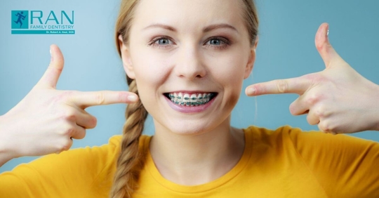 Girl with braces pointing towards her teeth